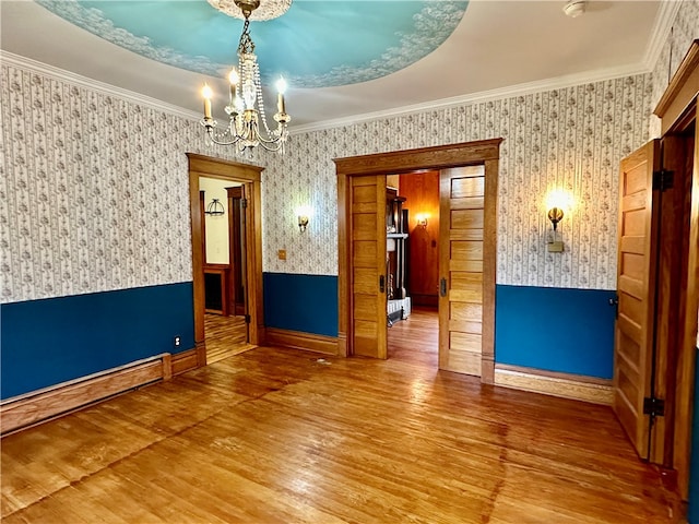 unfurnished room with a notable chandelier, baseboard heating, hardwood / wood-style flooring, and crown molding