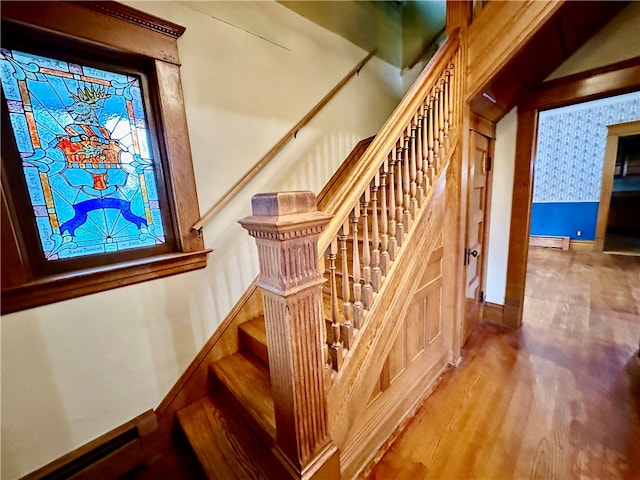 stairs featuring wood-type flooring and a baseboard heating unit