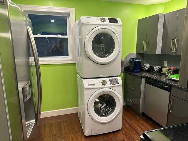 laundry room with dark hardwood / wood-style floors and stacked washer and clothes dryer