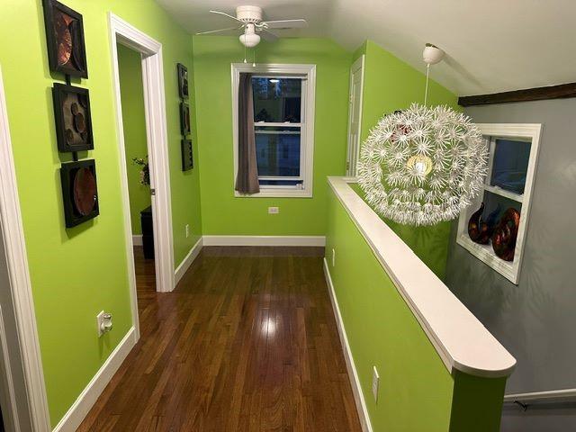 hallway with dark wood-type flooring and vaulted ceiling