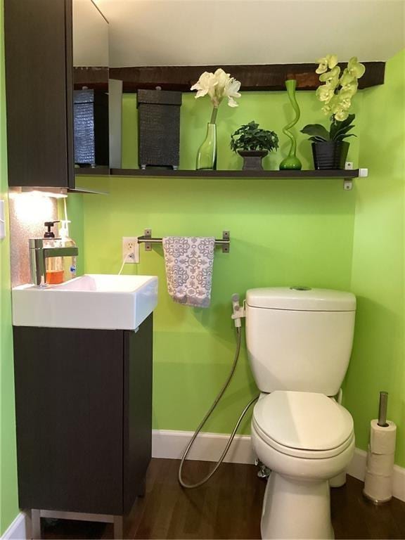 bathroom with wood-type flooring, vanity, and toilet