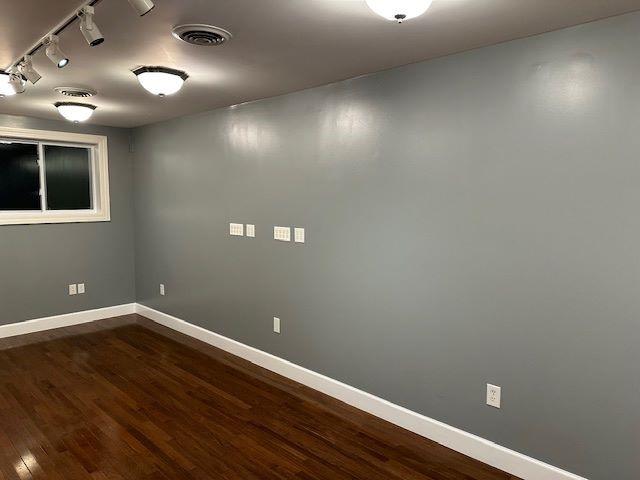 empty room with dark hardwood / wood-style flooring and track lighting