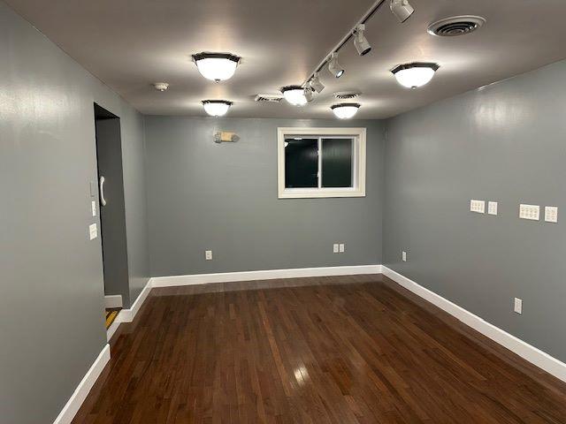 unfurnished room featuring dark hardwood / wood-style flooring and rail lighting