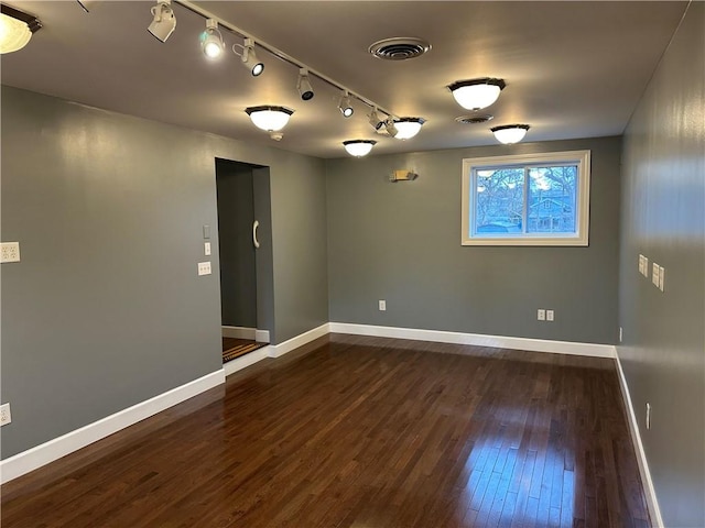 spare room with dark hardwood / wood-style floors and track lighting