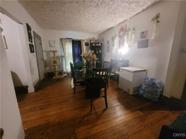 dining area with a textured ceiling and dark wood-type flooring