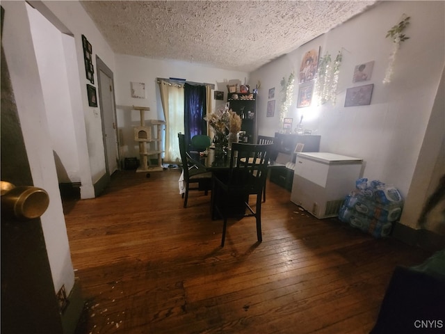 dining room with a textured ceiling and dark hardwood / wood-style floors