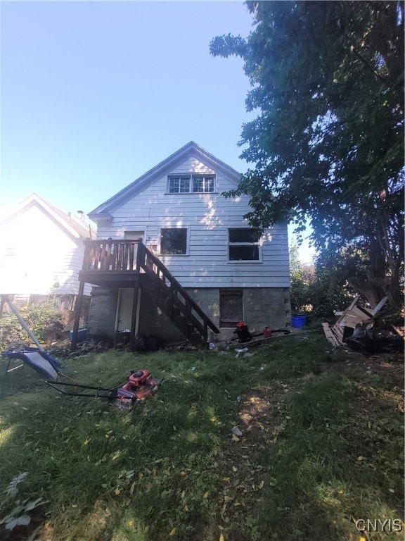 rear view of property featuring a lawn and a deck