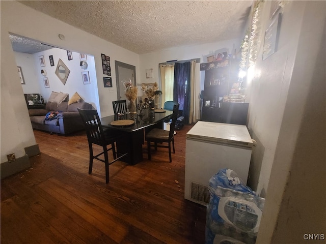 dining room with a textured ceiling and dark wood-type flooring