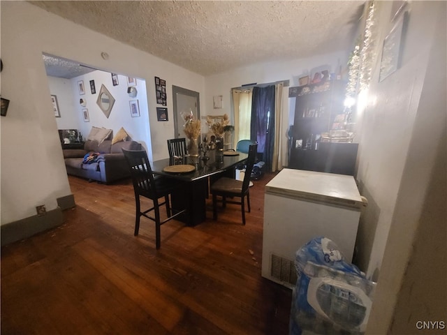 dining space with a textured ceiling and dark hardwood / wood-style floors