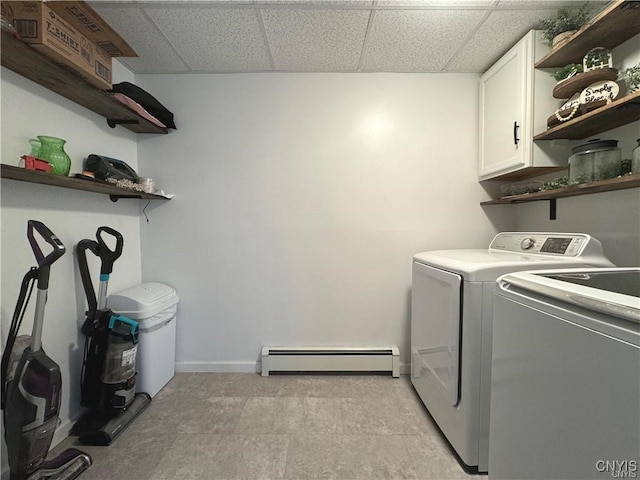 clothes washing area with cabinets, baseboard heating, and washer and clothes dryer