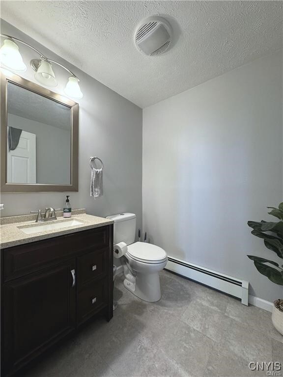 bathroom with a textured ceiling, vanity, toilet, and a baseboard radiator