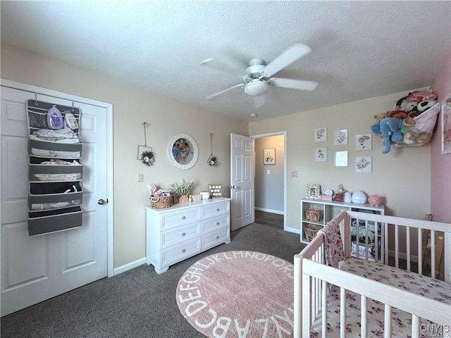 carpeted bedroom with ceiling fan, a nursery area, a textured ceiling, and a closet