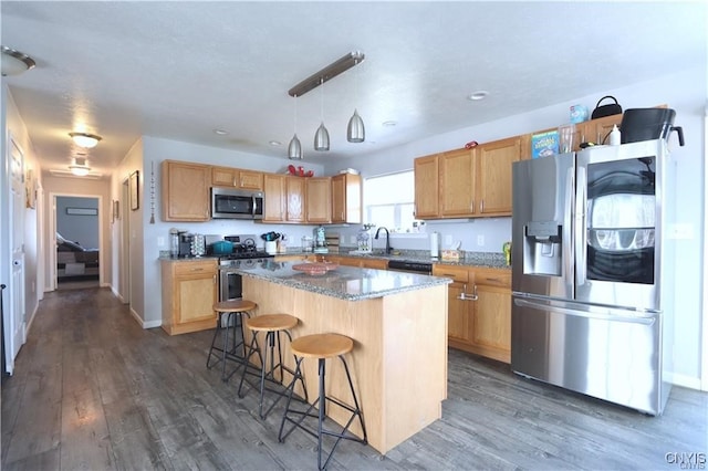 kitchen featuring a center island, dark hardwood / wood-style floors, sink, stainless steel appliances, and decorative light fixtures