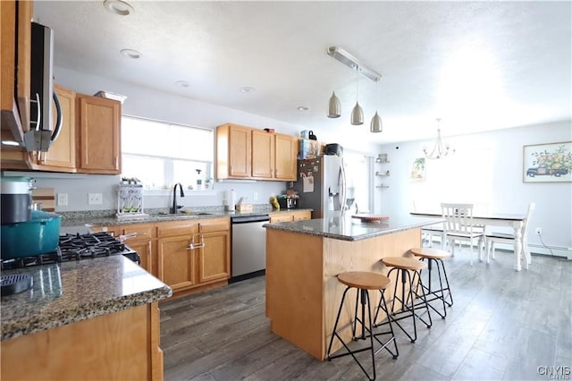 kitchen featuring dark wood-type flooring, appliances with stainless steel finishes, a kitchen island, and a breakfast bar area