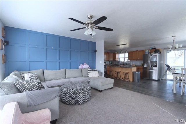 living room with ceiling fan with notable chandelier, dark hardwood / wood-style floors, and sink