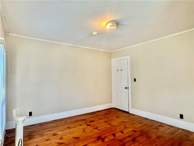 empty room with hardwood / wood-style flooring and crown molding