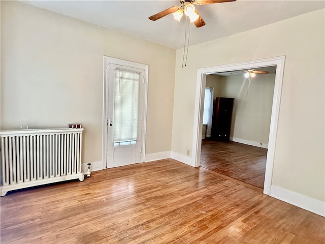 unfurnished room with wood-type flooring, radiator, and ceiling fan