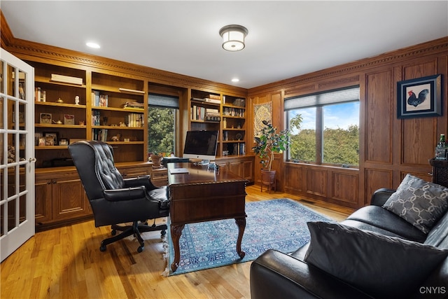 office area featuring light wood-type flooring, wood walls, and built in features