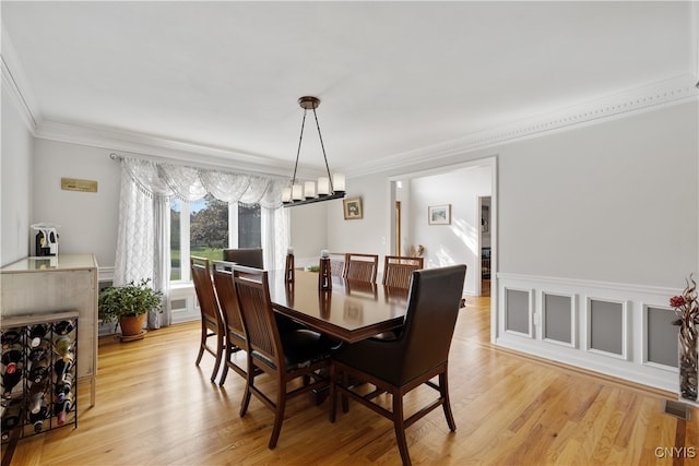 dining area featuring light hardwood / wood-style flooring, crown molding, and a chandelier