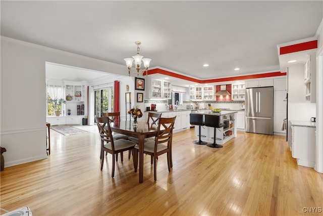 dining area with an inviting chandelier, light hardwood / wood-style floors, and ornamental molding