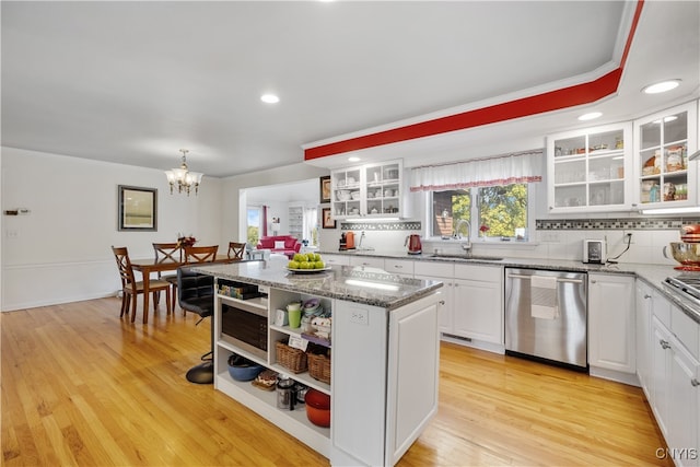 kitchen with white cabinets, a kitchen island, stainless steel appliances, light hardwood / wood-style flooring, and sink