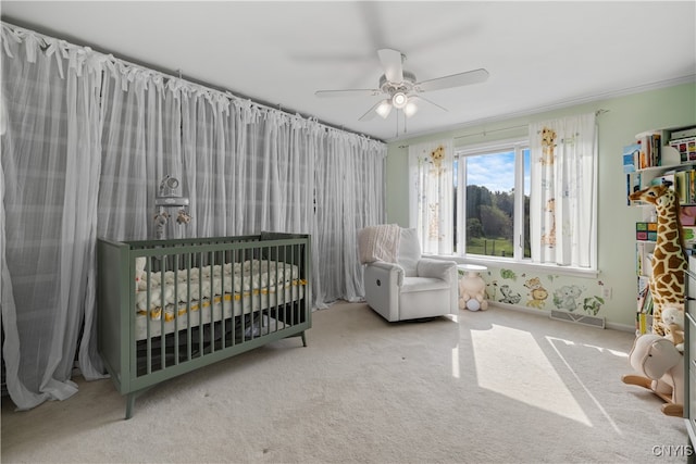 bedroom with carpet, crown molding, ceiling fan, and a nursery area