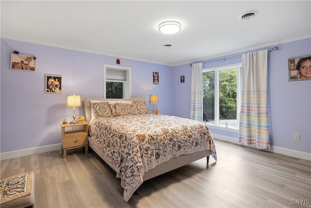 bedroom with light wood-type flooring and ornamental molding