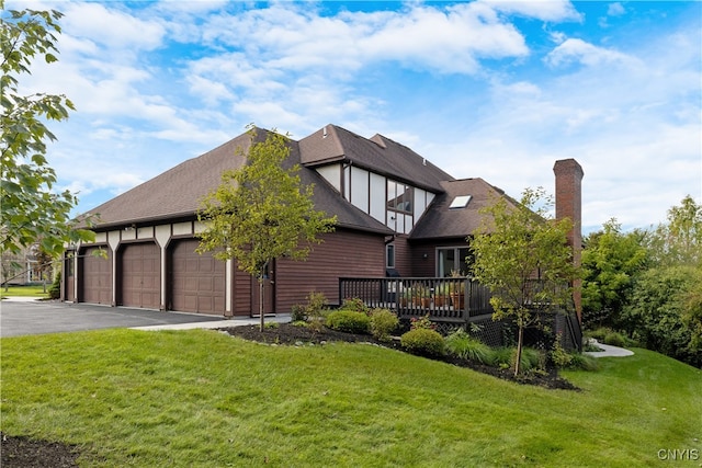 view of front of home featuring a front yard, a garage, and a wooden deck