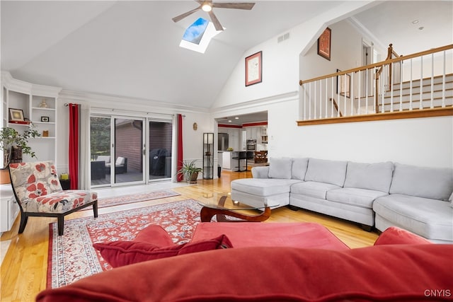 living room with high vaulted ceiling, wood-type flooring, ceiling fan, and a skylight