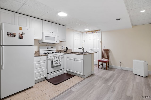 kitchen with light hardwood / wood-style flooring, white appliances, kitchen peninsula, and white cabinetry