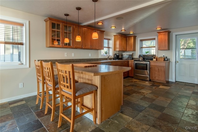 kitchen with appliances with stainless steel finishes, kitchen peninsula, vaulted ceiling, decorative light fixtures, and a breakfast bar