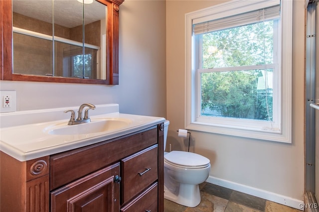 bathroom featuring vanity, a shower with shower door, toilet, and plenty of natural light