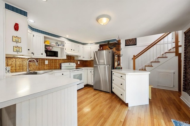 kitchen with white cabinetry, kitchen peninsula, stainless steel fridge, and white electric range oven