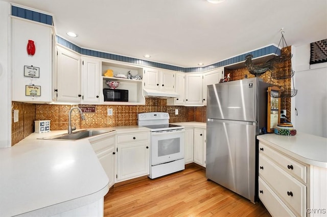 kitchen featuring white cabinets, white range with electric stovetop, stainless steel refrigerator, and sink