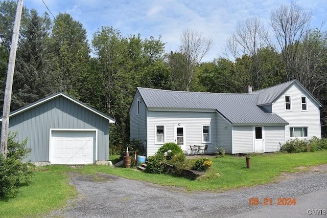 view of front of home with driveway, a garage, a chimney, metal roof, and a front lawn