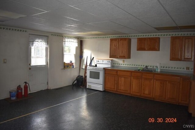 kitchen featuring white electric stove, brown cabinetry, a sink, and a paneled ceiling