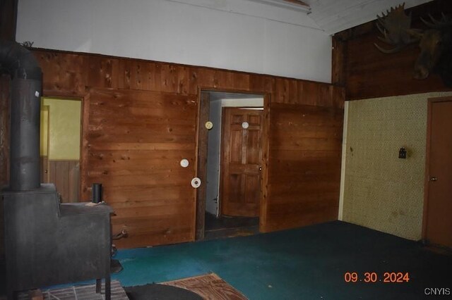 unfurnished bedroom with a wood stove and wood walls