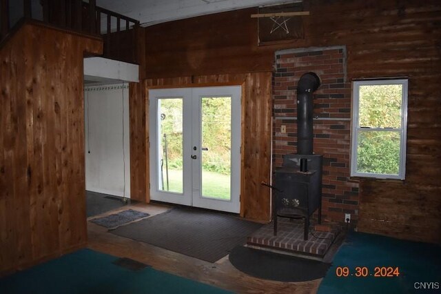 doorway with a wood stove, wooden walls, and french doors