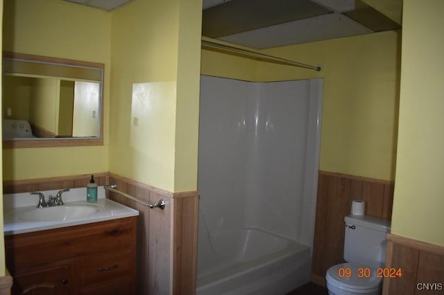 full bath with shower / bathing tub combination, toilet, wainscoting, wooden walls, and vanity