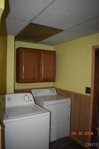 laundry area with washer and clothes dryer, wainscoting, cabinet space, and wooden walls