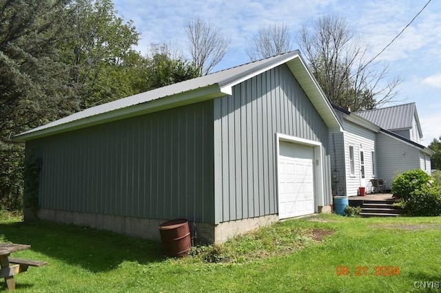 view of side of property with a garage, metal roof, board and batten siding, and a yard