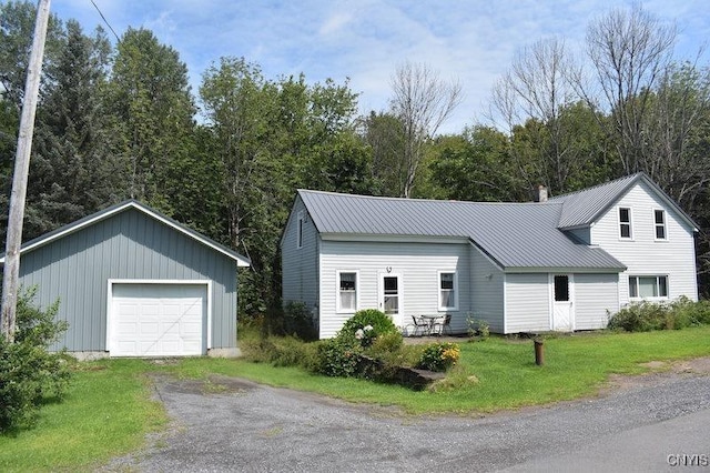 view of front of home with a chimney, a front yard, metal roof, a garage, and driveway