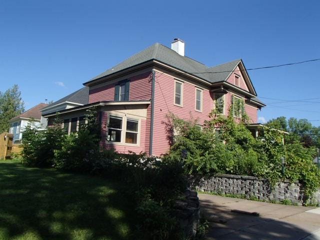 view of home's exterior featuring a chimney and a yard