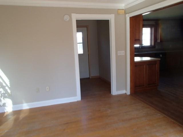 interior space with light wood-type flooring, crown molding, and baseboards