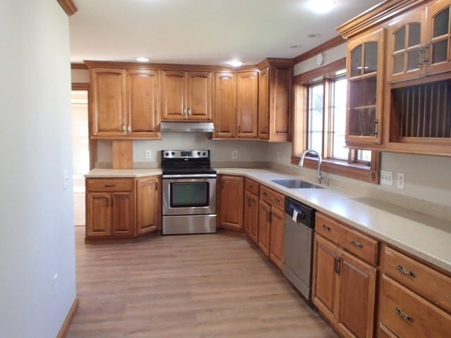 kitchen featuring stainless steel appliances, crown molding, sink, and light hardwood / wood-style flooring