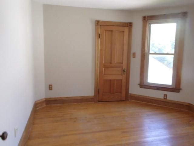 spare room featuring light wood finished floors, baseboards, and a wealth of natural light