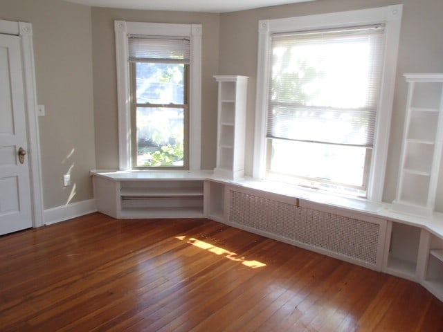 unfurnished room with hardwood / wood-style flooring, radiator heating unit, and a wealth of natural light