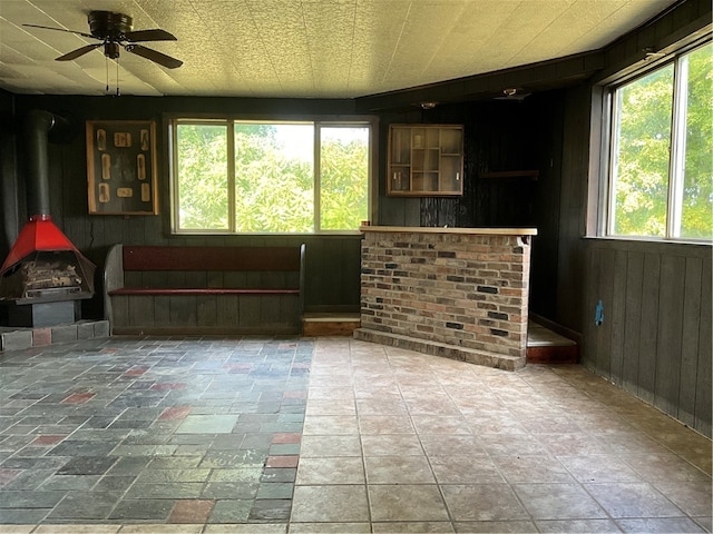 interior space with wood walls, ceiling fan, and plenty of natural light