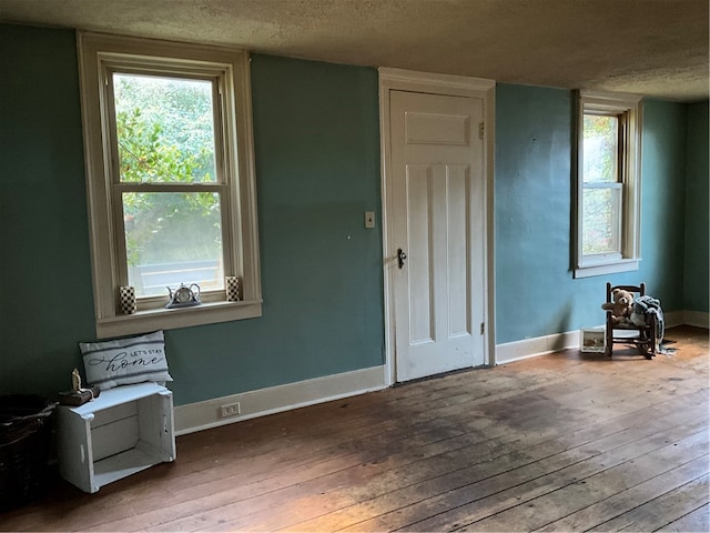 interior space with a textured ceiling and hardwood / wood-style floors