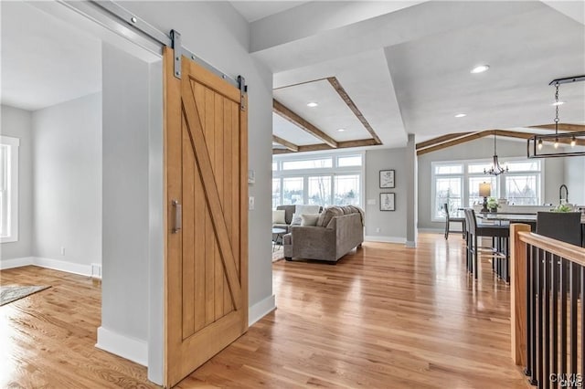 interior space with vaulted ceiling with beams, a chandelier, plenty of natural light, and a barn door